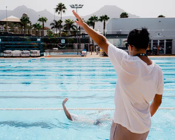 swimming coach in the pool showing the movement. 